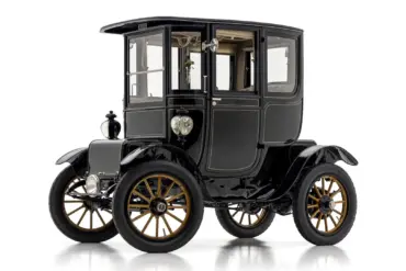 Seitenansicht eines restaurierten 1912 Baker Electric Model V Special Extension Coupe mit schwarz-goldenen Rädern und klassischer Aluminiumkarosserie.