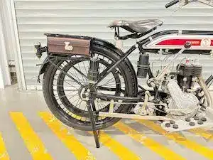 Detailfoto des historischen Motorrads Premier 499 cm³ von 1914 mit sichtbaren Antriebselementen, Sattel und Gepäckträger.