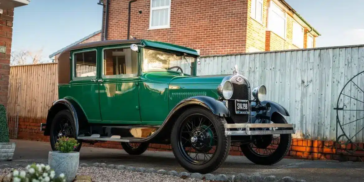 Grüner Ford Model A Baujahr 1928 mit schwarzem Dach und Speichenrädern steht vor einem Haus in der Einfahrt.