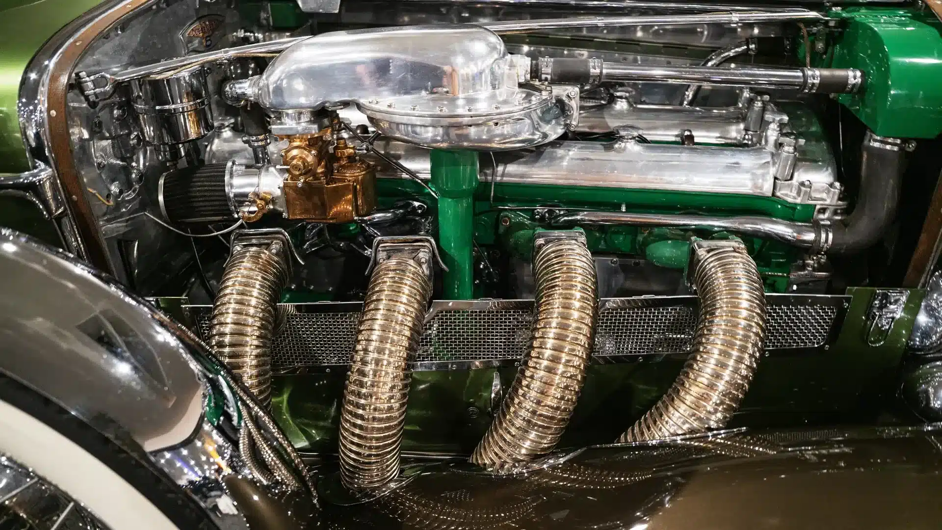 Nahaufnahme des Motors mit Kompressor des Duesenberg Model SJ von 1929 mit grünen Bauteilen und verchromten Luftschläuchen