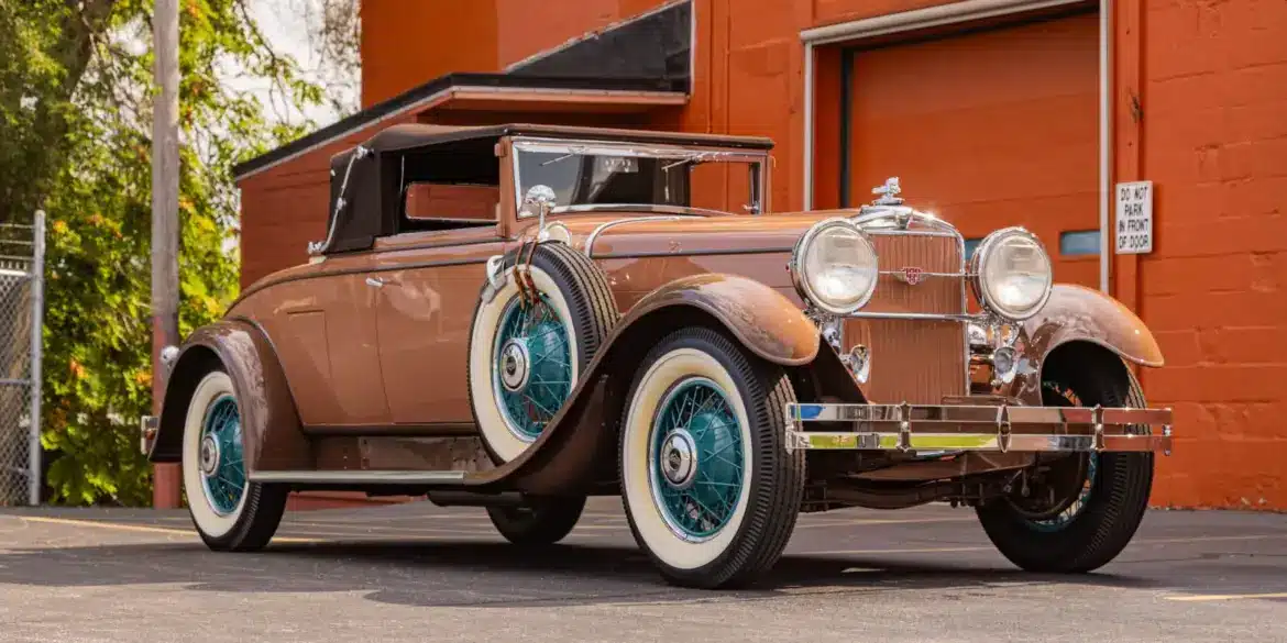 Seitenansicht eines restaurierten 1930 Stutz MB Convertible Coupe mit beigem Lack, weißen Reifen und blauen Speichenfelgen.