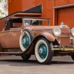 Seitenansicht eines restaurierten 1930 Stutz MB Convertible Coupe mit beigem Lack, weißen Reifen und blauen Speichenfelgen.