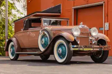 Seitenansicht eines restaurierten 1930 Stutz MB Convertible Coupe mit beigem Lack, weißen Reifen und blauen Speichenfelgen.