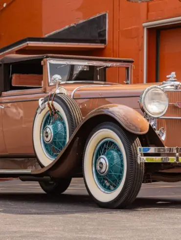 Seitenansicht eines restaurierten 1930 Stutz MB Convertible Coupe mit beigem Lack, weißen Reifen und blauen Speichenfelgen.
