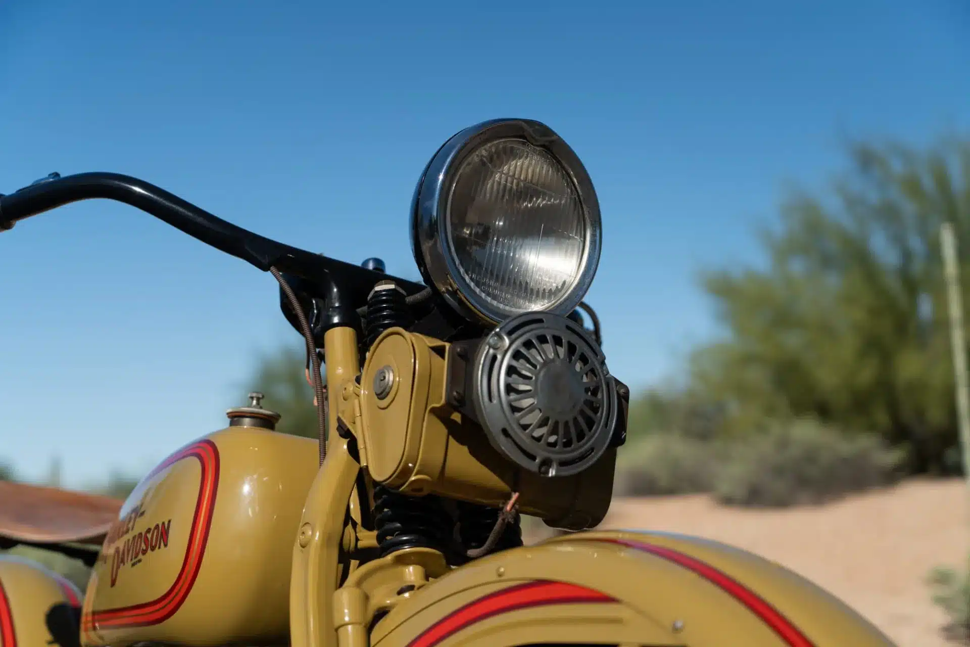 Scheinwerfer und Tank einer 1932 Harley-Davidson VL Big Twin in originaler Zweifarbenlackierung, aufgenommen bei Tageslicht.