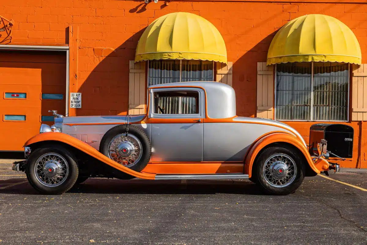 Restauriertes Packard Model 902 Eight Coupé von 1932 in Silber und Orange vor einer orangen Hauswand mit gelben Markisen