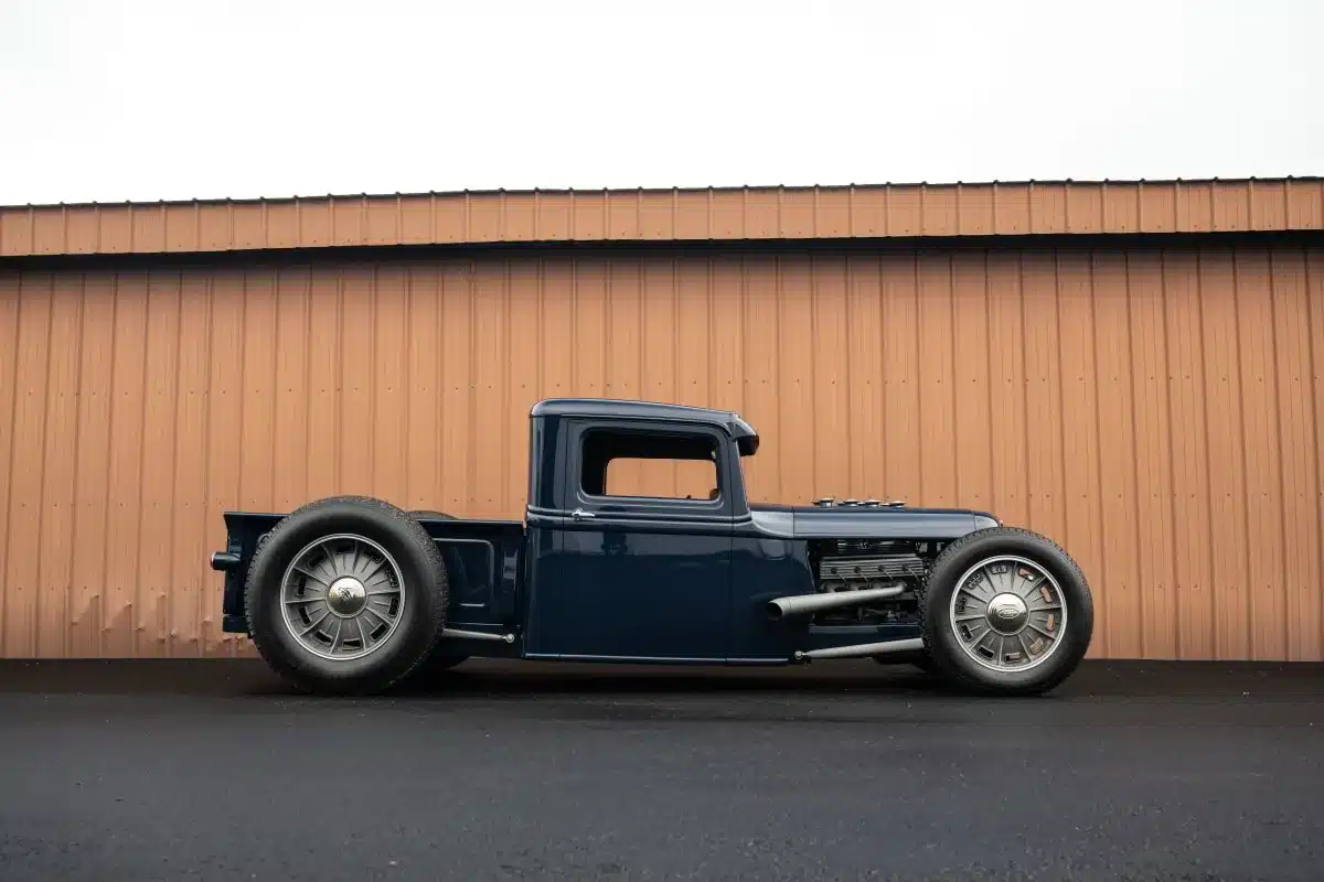 Seitliche Ansicht eines restaurierten 1934 Ford Model A Hot Rod Pickups im Hot Rod Stil vor einer Blechhalle.