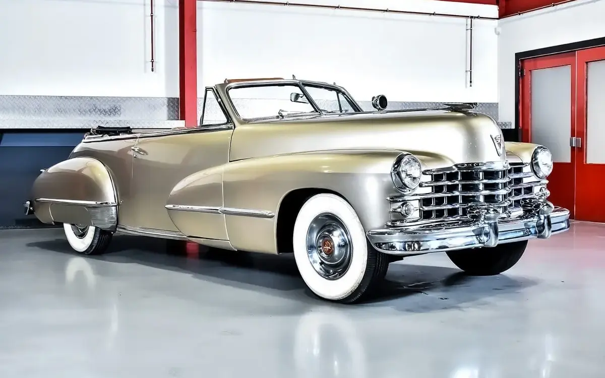 Cadillac Series 62 Cabriolet von 1947 in metallic Champagnergold, restauriert, mit offenem Verdeck und weißwandbereiften Rädern.
