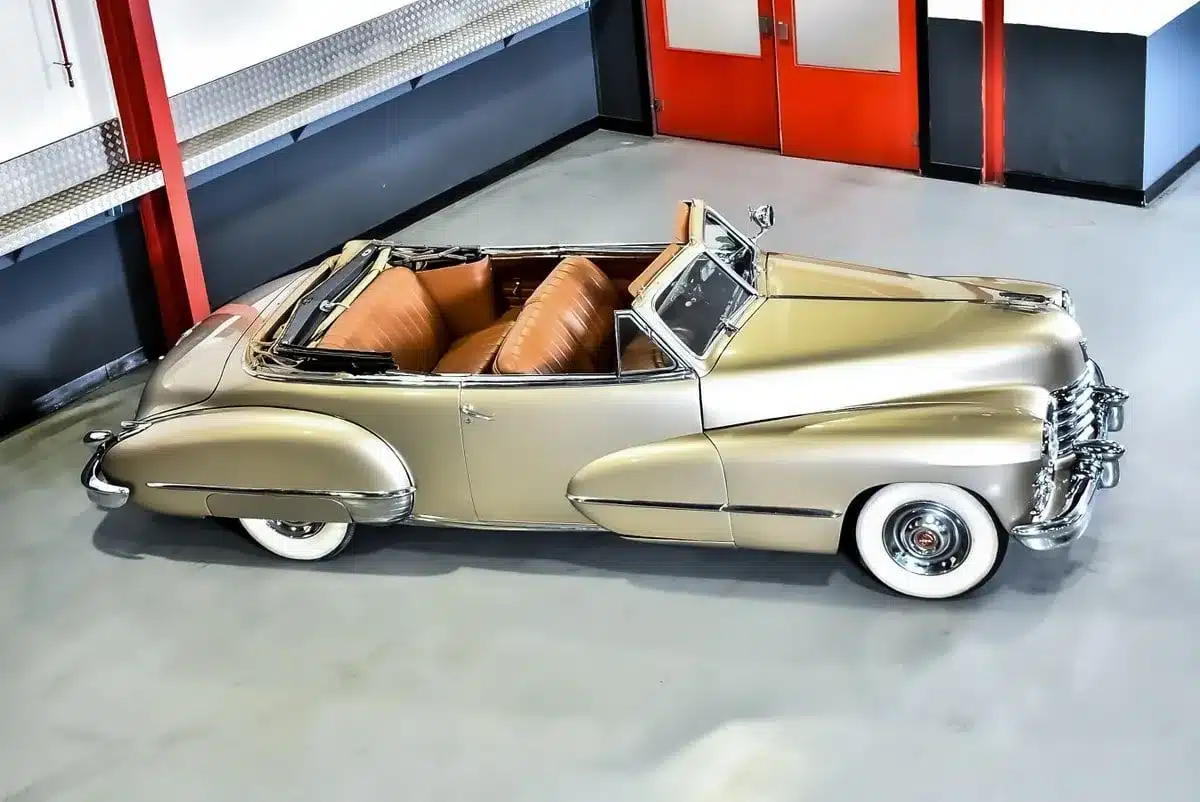 Seitenansicht eines restaurierten Cadillac Series 62 Cabriolets von 1947, metallic Champagnergold, mit offenem Verdeck und beigem Lederinterieur