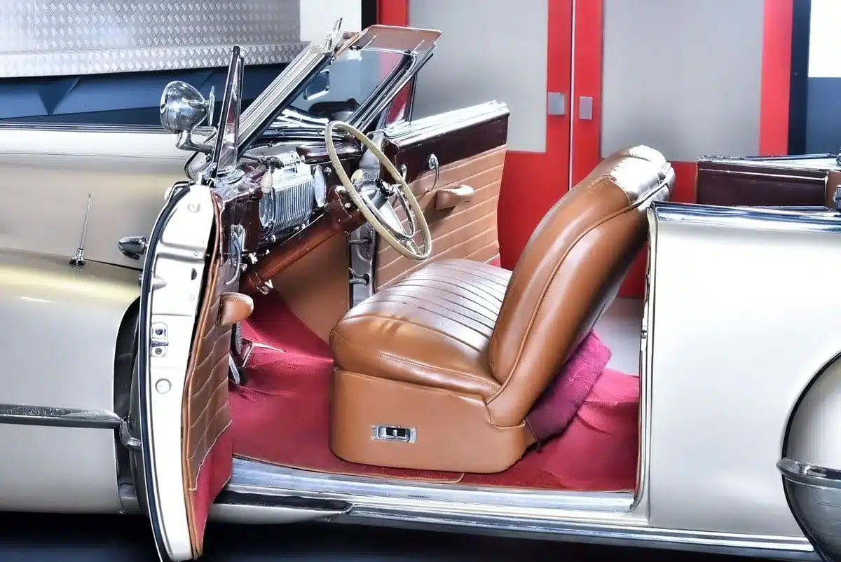 Restaurierter Innenraum eines Cadillac Series 62 Cabriolets von 1947 mit beigen Ledersitzen und rotem Teppich.