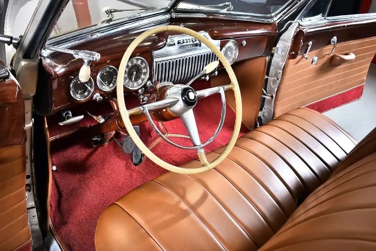 Armaturenbrett und Sitze eines restaurierten Cadillac Series 62 Cabriolet von 1947, mit originalem Lenkrad und beigefarbenem Lederinterieur.