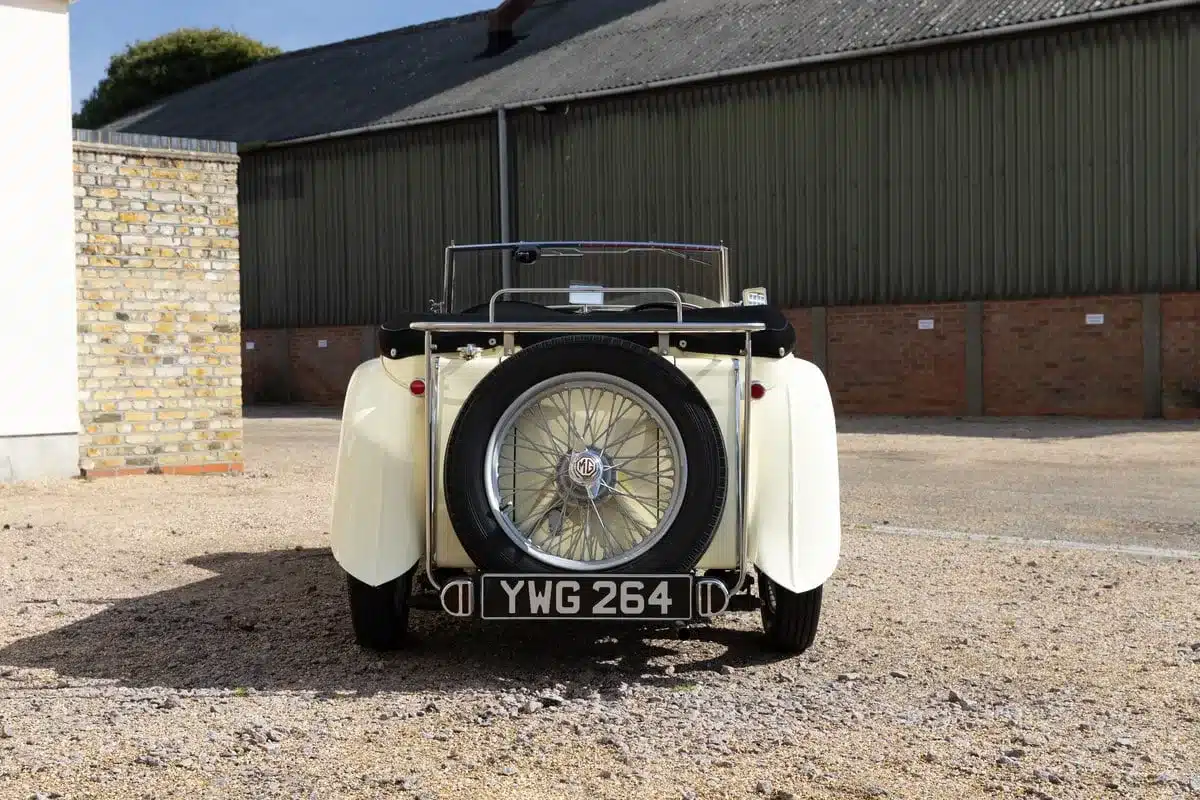 Heckansicht eines hellen MG TC Midget von 1948 mit offenem Verdeck und Reserverad.