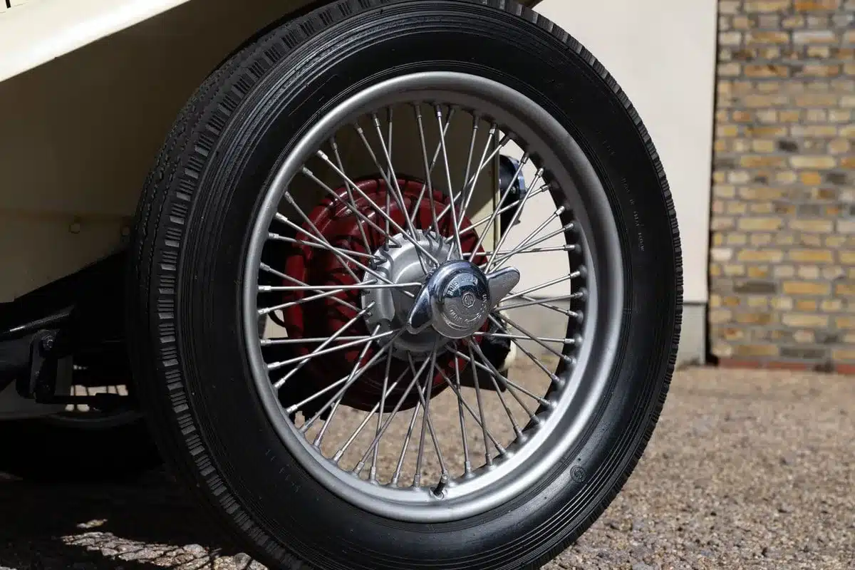 Restauriertes Drahtspeichenrad eines 1948 MG TC Midget, silber mit roter Radnabe und Chrommutter.