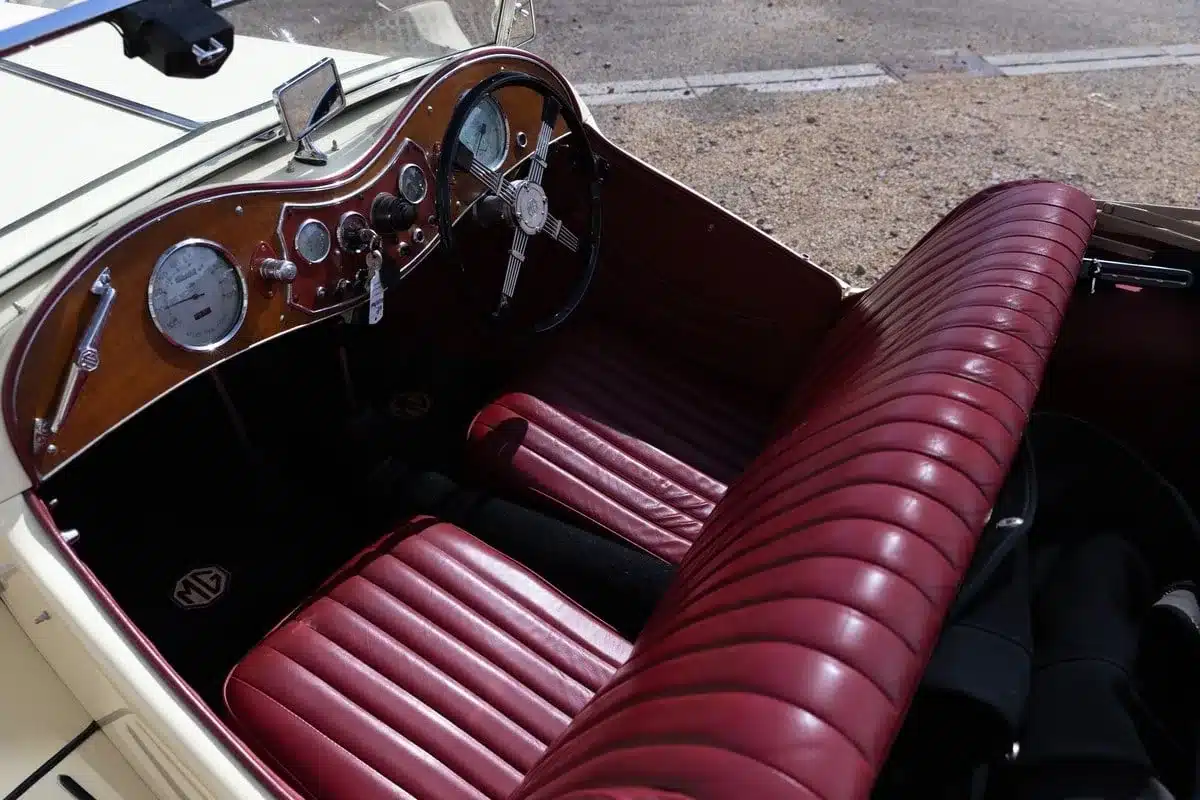 Blick auf das rote Lederinterieur und das Armaturenbrett eines MG TC Midget von 1948 mit Holz- und Chromdetails.