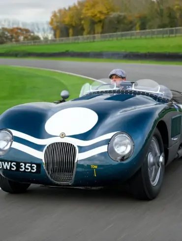 Jaguar C-Type XKC 006 in Dunkelgrün mit weißer Startnummer auf Rennstrecke, Frontansicht, Fahrer mit Schiebermütze