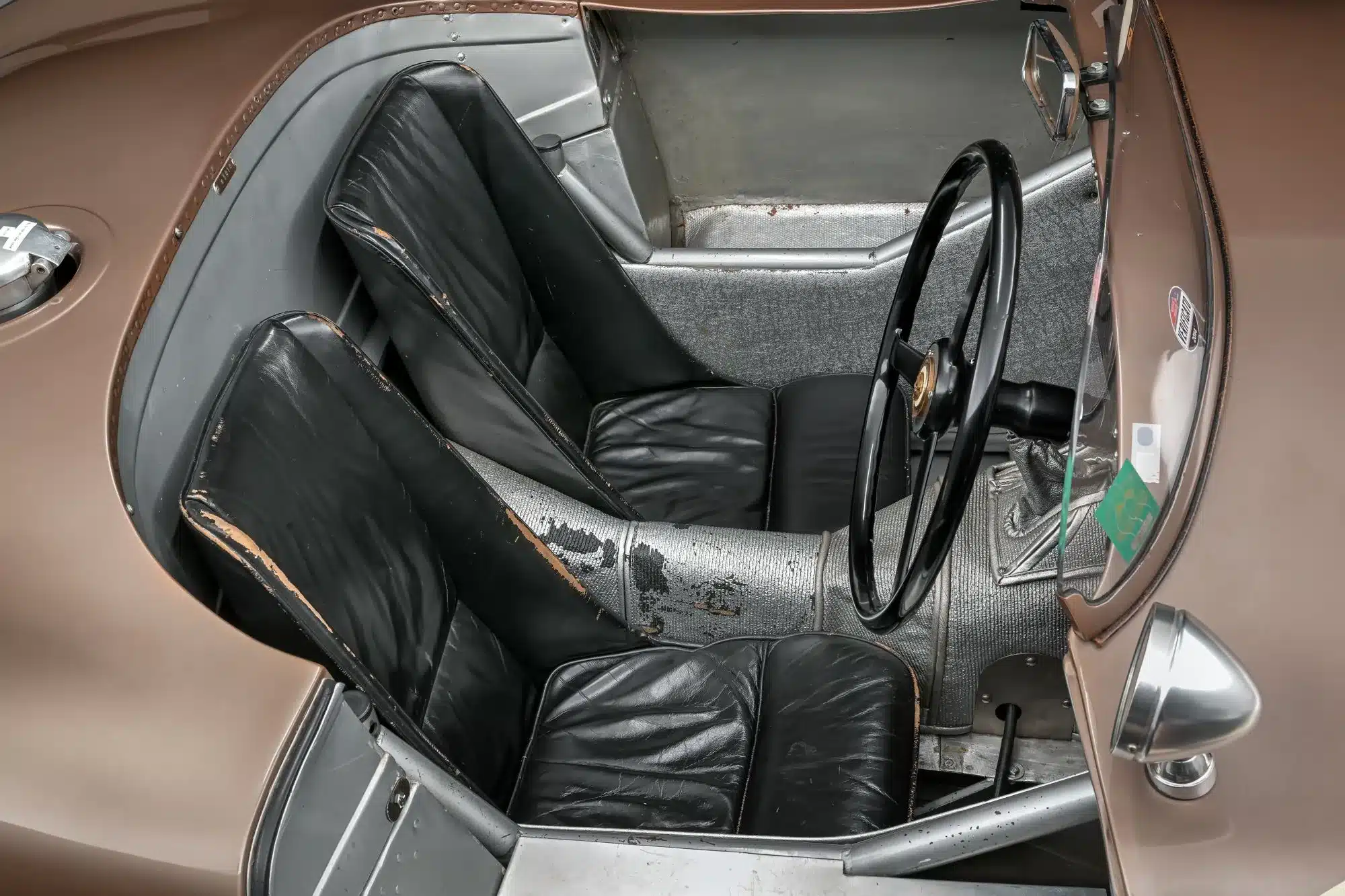 Cockpit des Jaguar C-Type XKC 018 mit abgenutzten Ledersitzen und originalem, unrestauriertem Interieur.