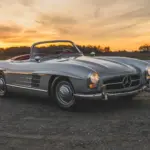 1957 Mercedes-Benz 300 SL Roadster in Silber mit rotem Lederinterieur und offenem Verdeck bei Sonnenuntergang
