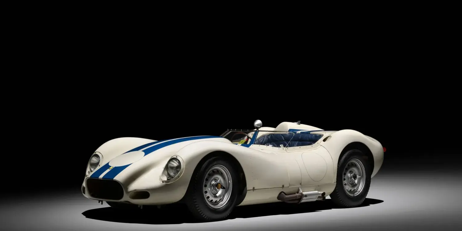 Originaler 1958 Lister Knobbly Chevrolet mit weißer Lackierung und blauen Streifen, fotografiert vor schwarzem Hintergrund.