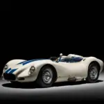 Originaler 1958 Lister Knobbly Chevrolet mit weißer Lackierung und blauen Streifen, fotografiert vor schwarzem Hintergrund.