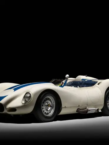 Originaler 1958 Lister Knobbly Chevrolet mit weißer Lackierung und blauen Streifen, fotografiert vor schwarzem Hintergrund.