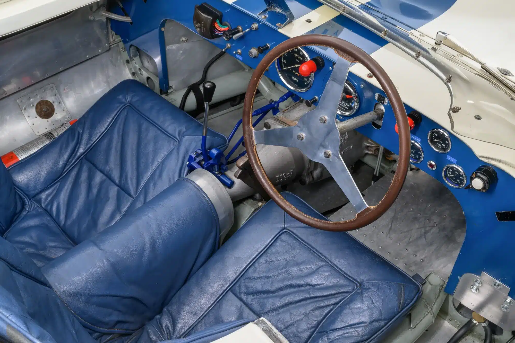 Innenraum des 1958 Lister Knobbly Chevrolet mit blauem Ledersitz, klassischem Lenkrad und Instrumententafel.