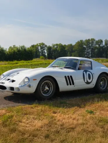 Weißer Ferrari 250 GTO von 1962 mit Rennnummer 10 auf einer Landstraße im Grünen.