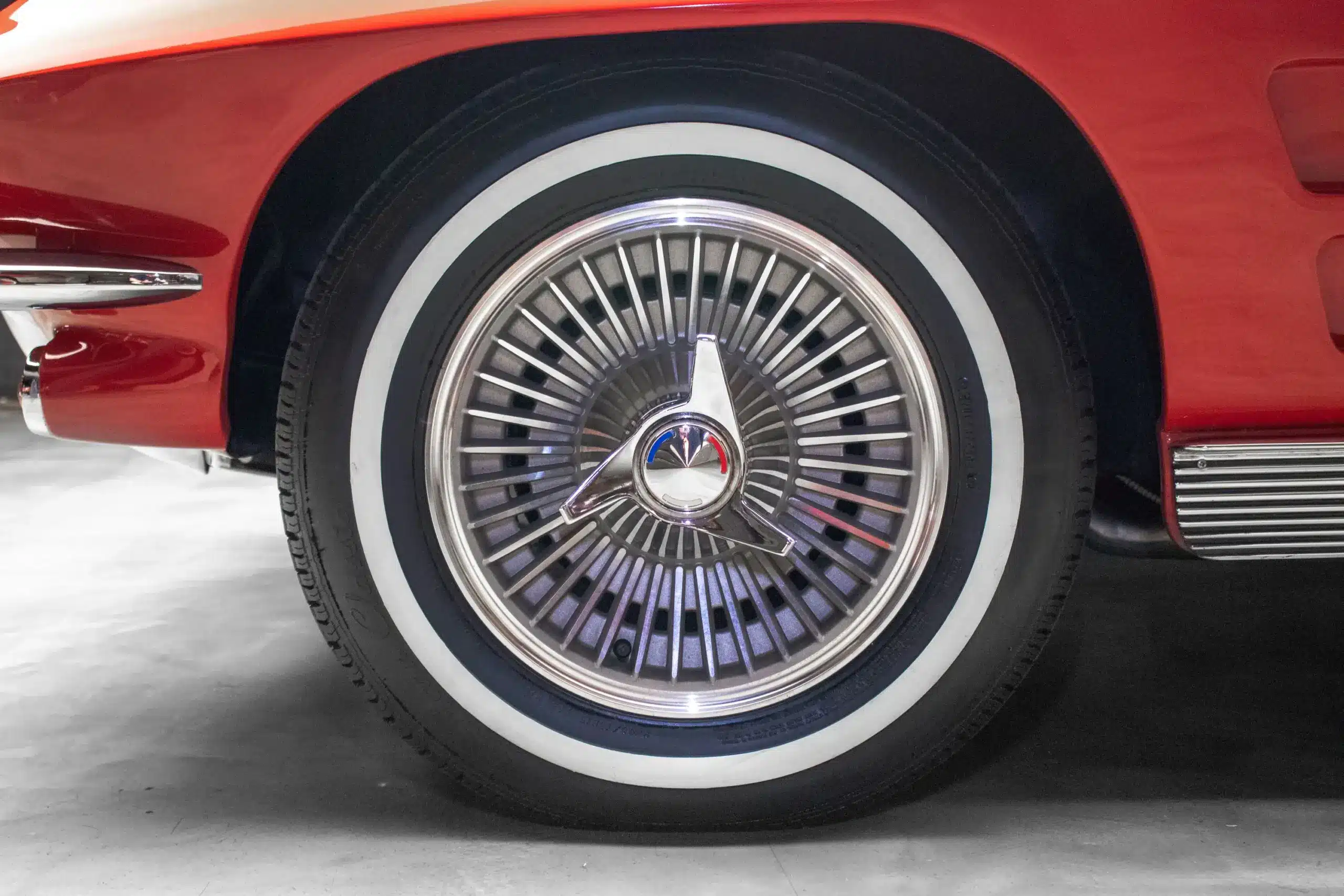 Detailaufnahme der 15-Zoll-Alufelge mit Knock-Off-Mittelverschluss und Weißwandreifen an einer Corvette C2 von 1963