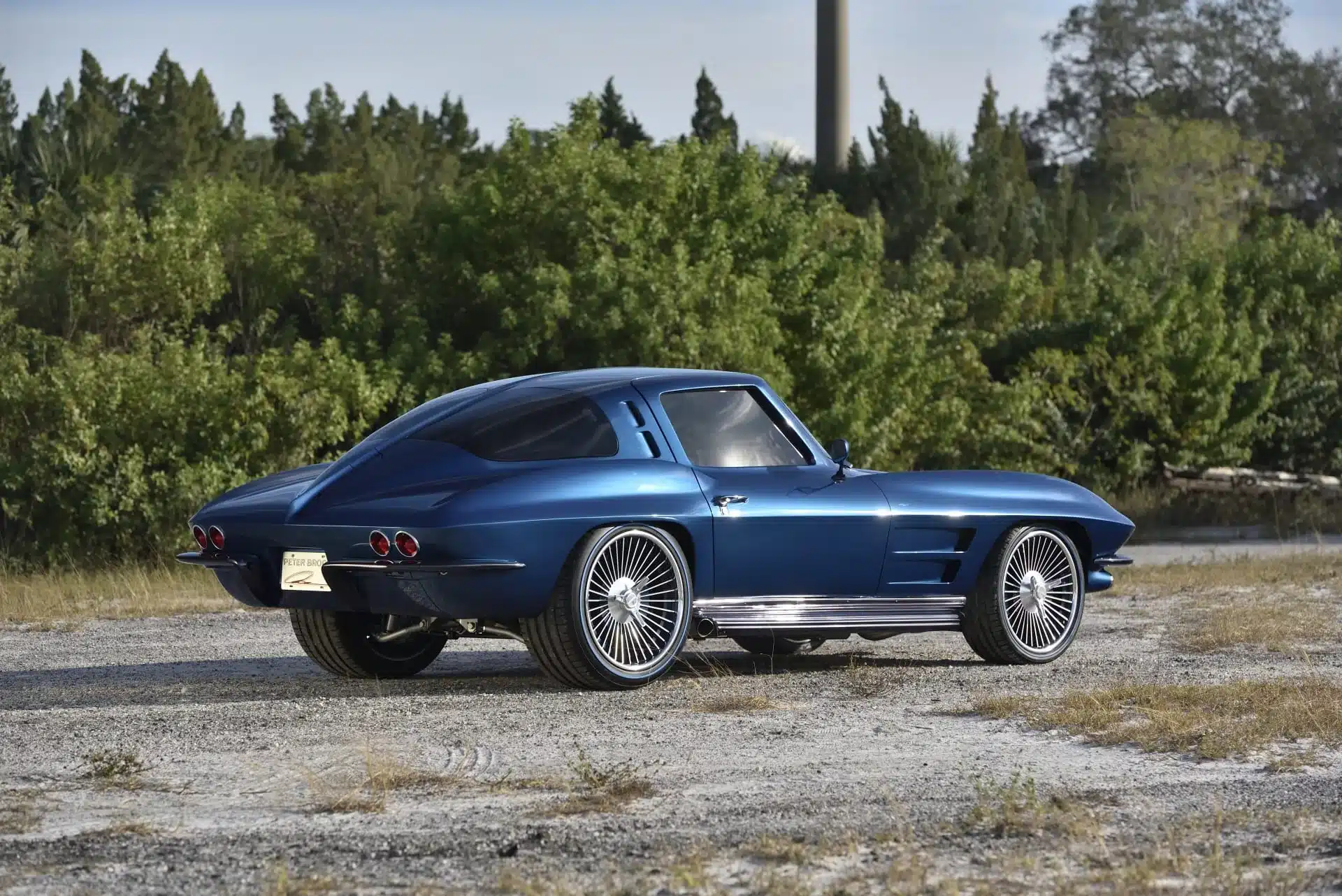 Blaue 1963 Chevrolet Corvette Split Window Studio Concept mit geteiltem Heckfenster im Profil, geparkt auf offener Fläche.
