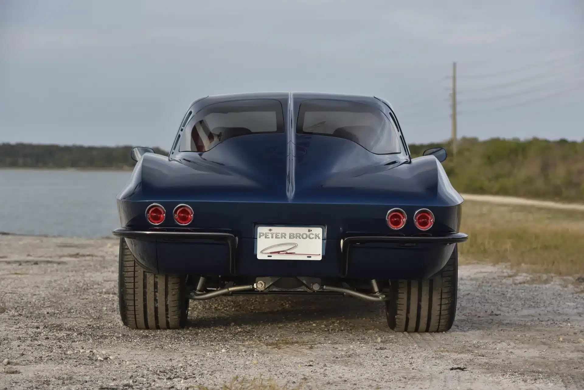 Heckansicht einer dunkelblauen 1963 Chevrolet Corvette Split Window mit geteiltem Rückfenster, fotografiert am Wasser.