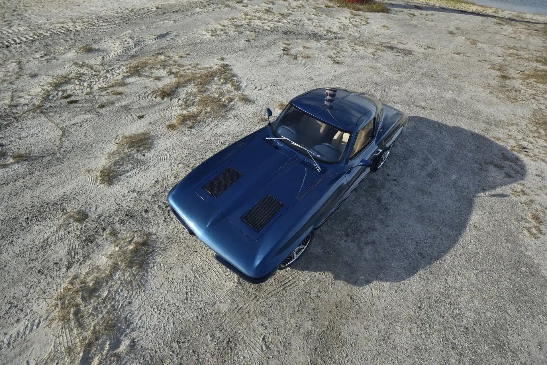 Blaue 1963 Chevrolet Corvette Split Window von oben auf sandigem Untergrund fotografiert.