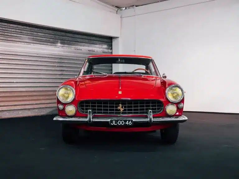 Restaurierter roter Ferrari 250 GTE 2+2 Series III von 1963, frontal fotografiert, in einer Halle.