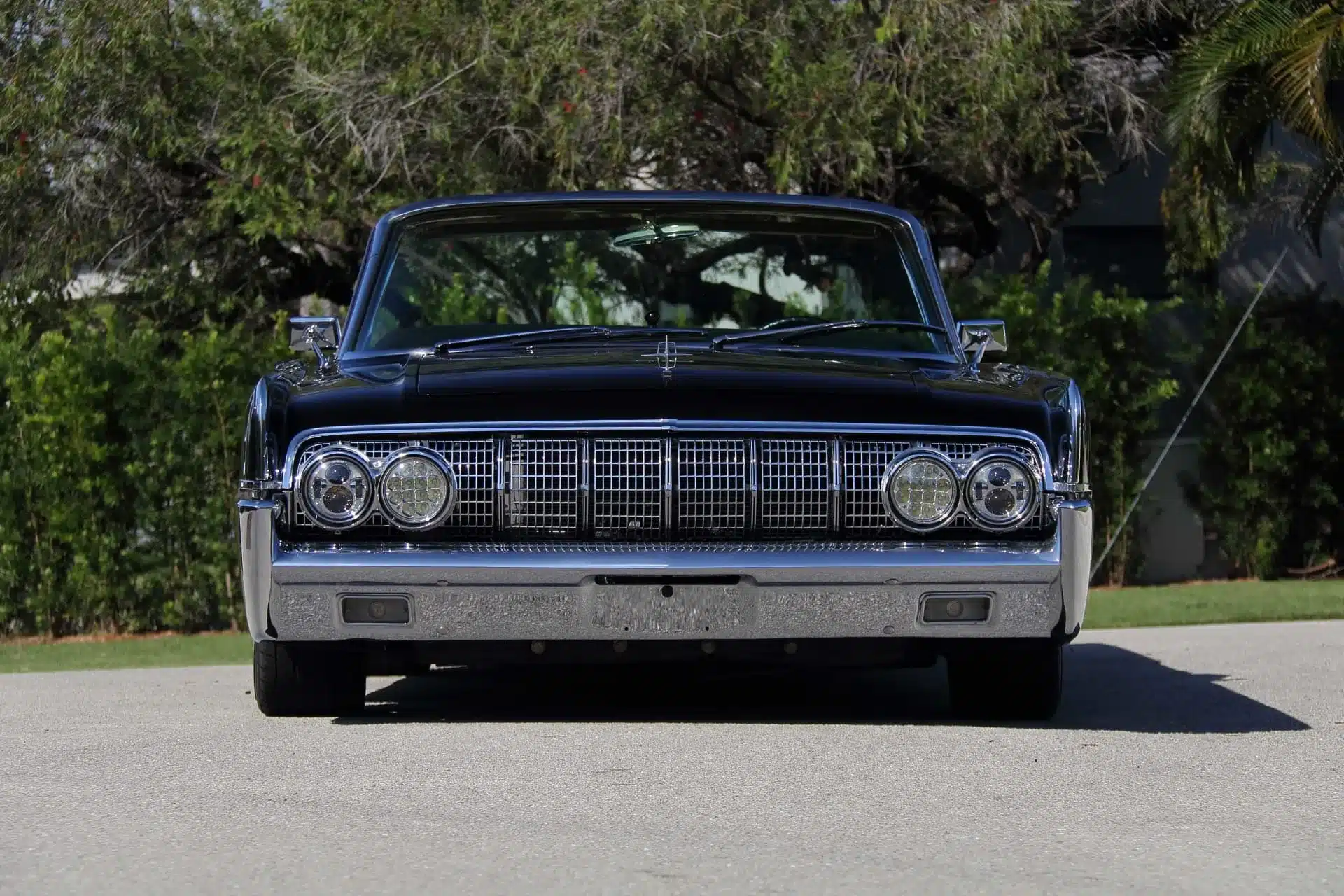 Frontansicht eines schwarzen 1964 Lincoln Continental Cabriolets, deutliche Chromdetails und markante Doppelscheinwerfer.