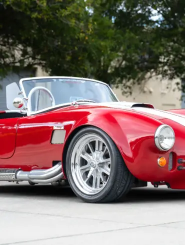 1965 Ford Backdraft Cobra Replika in rot mit weißen Streifen, aufgenommen auf einem Parkplatz.
