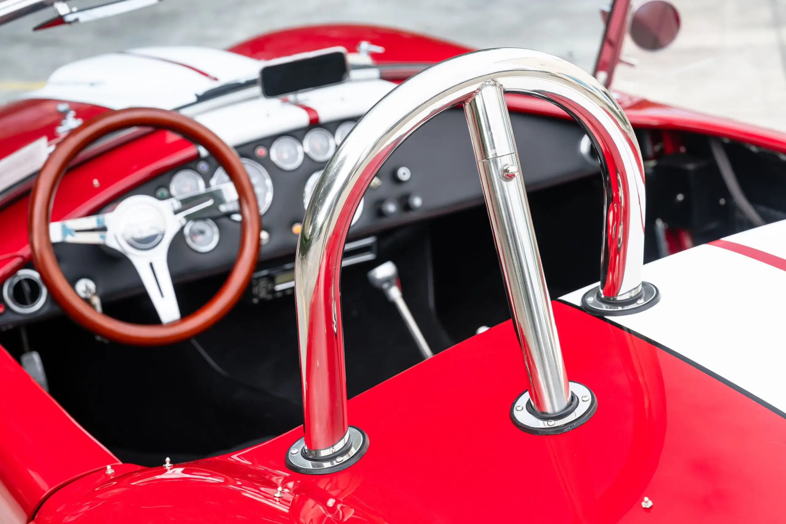 Innenraum einer 1965 Ford Backdraft Cobra mit Holzlenkrad, Rundinstrumenten und Chrom-Überrollbügel.