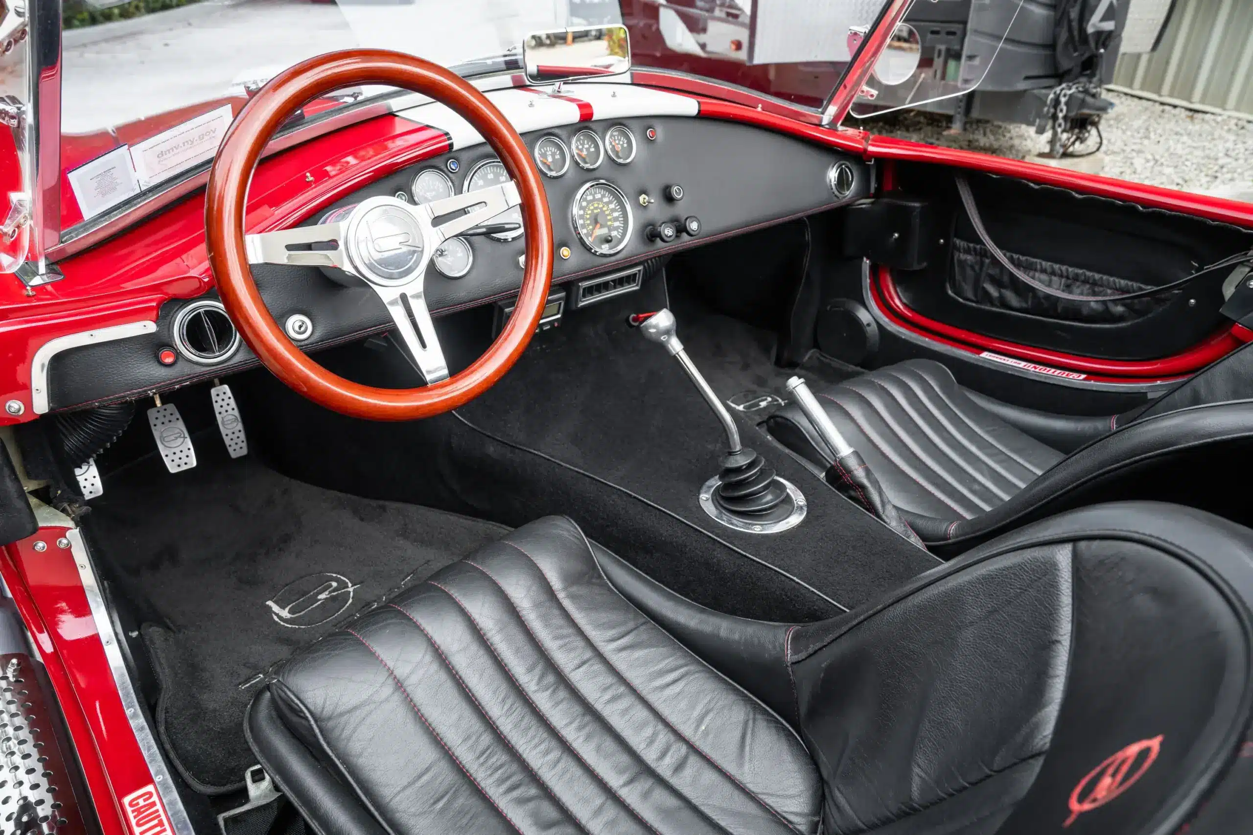 Innenraum der 1965 Ford Backdraft Cobra mit Holzlenkrad, Schaltknauf und schwarzen Ledersitzen mit roten Nähten