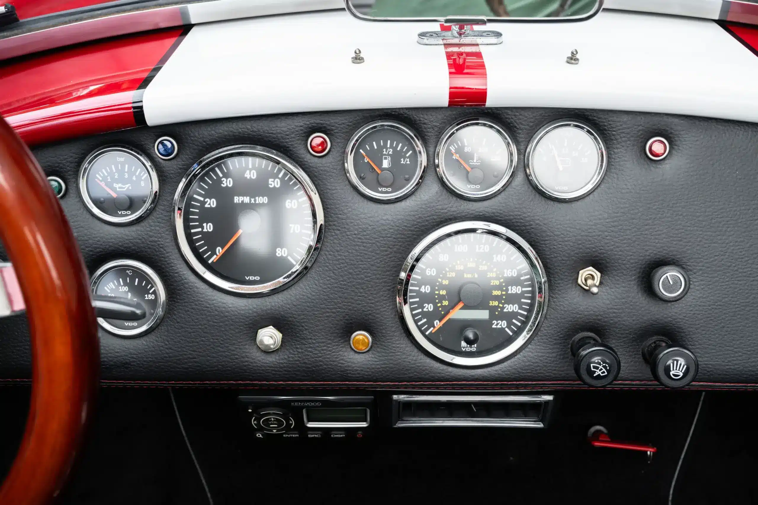 Armaturenbrett der 1965 Ford Backdraft Cobra mit klassischen VDO-Instrumenten, schwarzem Lederbezug und roten Ziernähten.