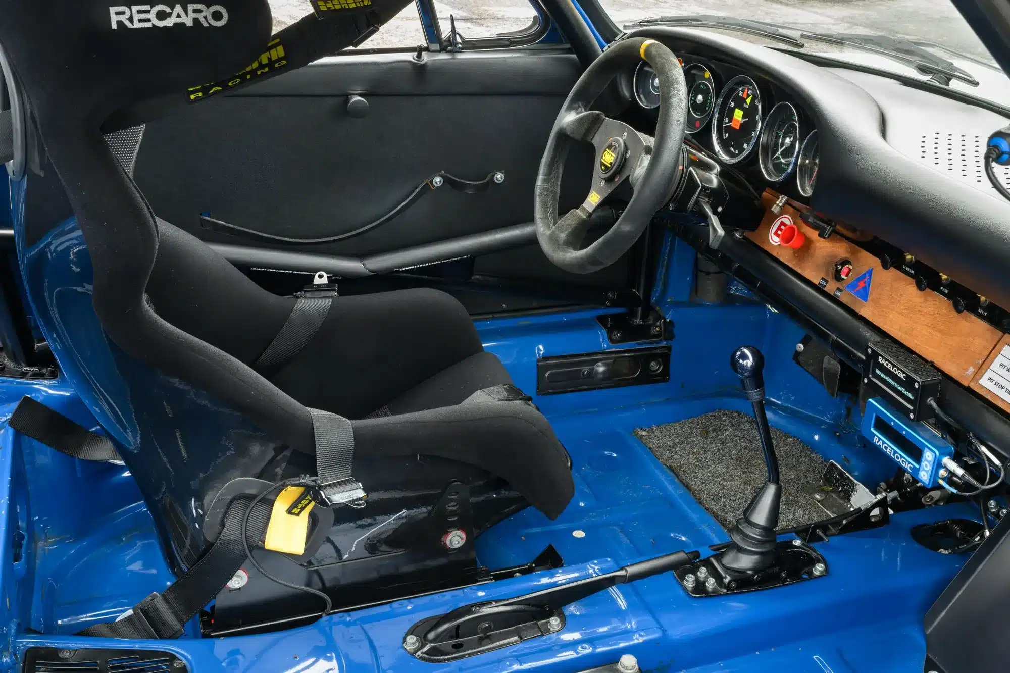 Rennsportoptimierter Innenraum eines blauen Porsche 911 von 1965 mit Recaro-Schalensitz, Überrollbügel und modifiziertem Cockpit.