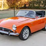 Sunbeam Tiger Mk1 Roadster in warmer Creamsicle-Perleffektlackierung, offen, auf einer Auffahrt.