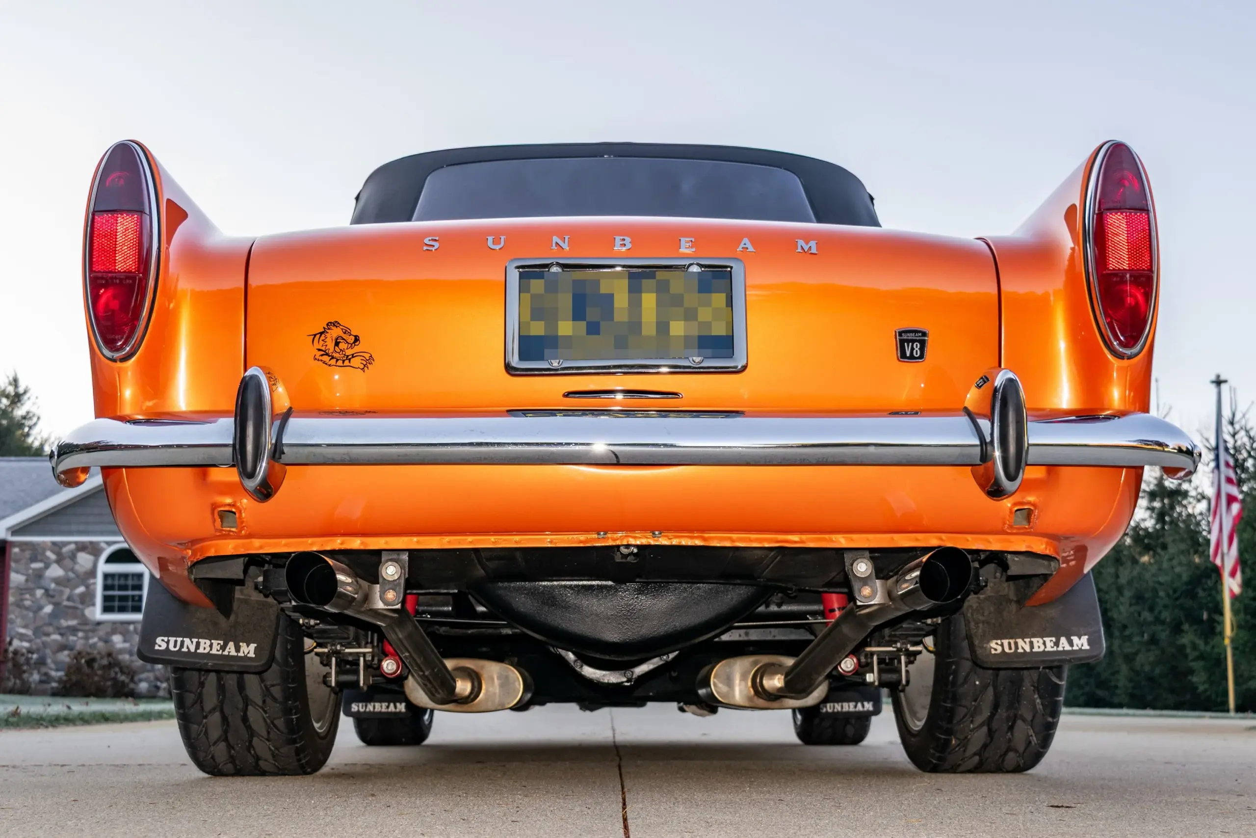 Heckansicht eines restaurierten Sunbeam Tiger Mk1 in oranger Creamsicle-Lackierung mit doppeltem Auspuff und Sunbeam-Schriftzug