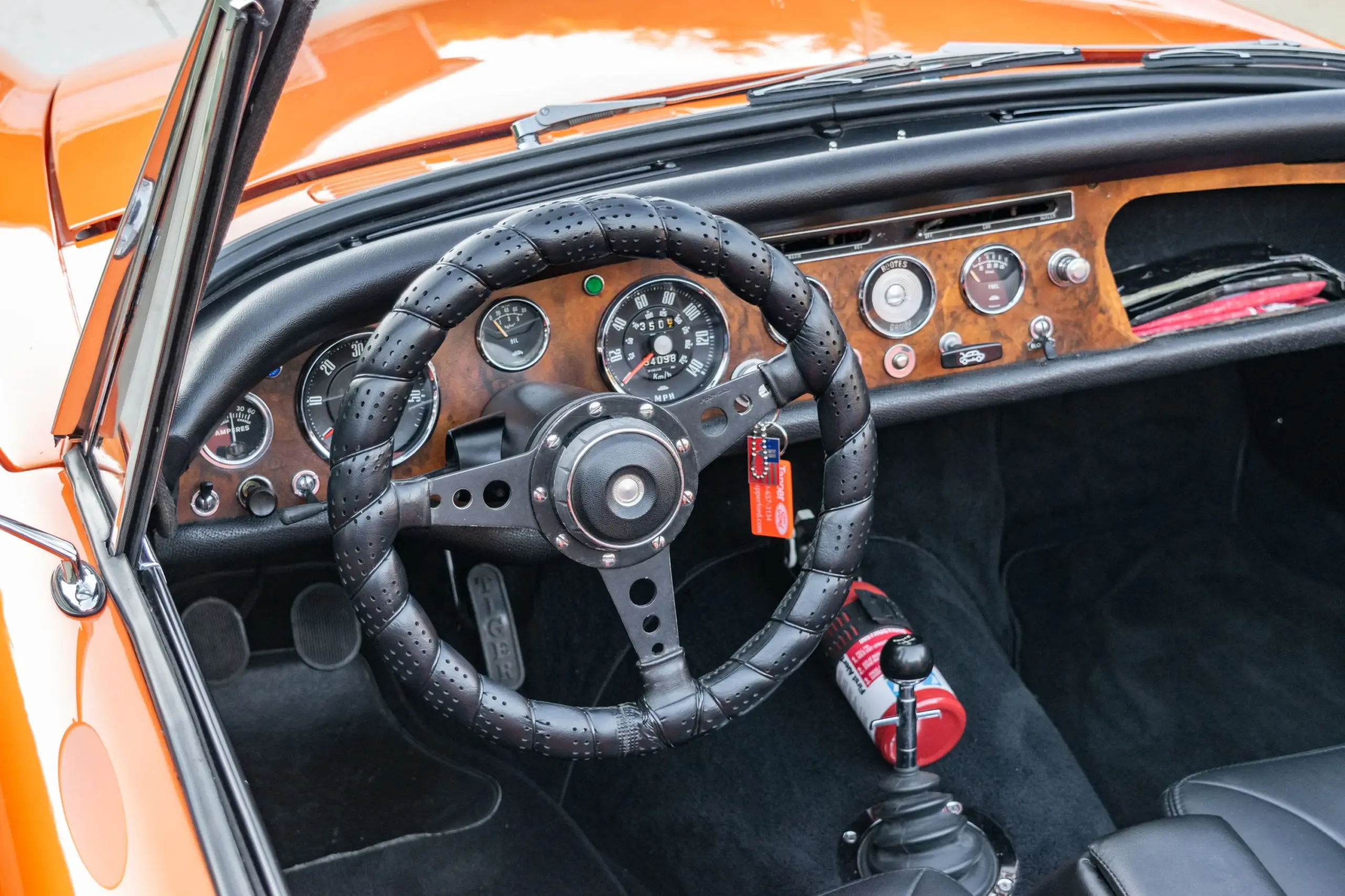 Innenraum eines restaurierten Sunbeam Tiger Mk1 mit Holz-Armaturenbrett, Ledersitzen, Sportlenkrad und Feuerlöscher