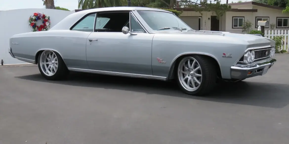 1966 Chevrolet Chevelle SS 396 silberfarben, seitlich aufgenommen vor Wohnhaus und Palmen.