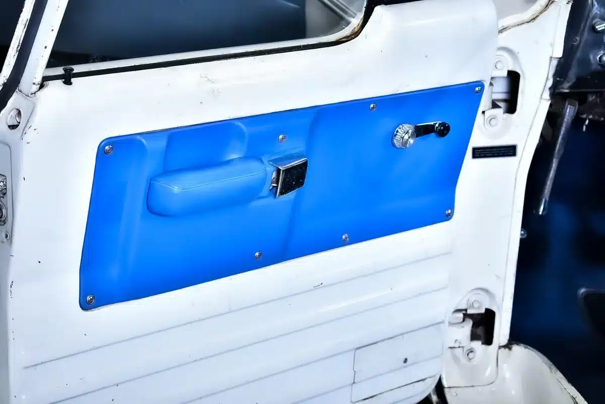 Innenansicht einer weißen Fahrzeugtür mit blauer Türverkleidung und mechanischem Fensterheber, vermutlich aus einem Dodge D100 Baujahr 1968