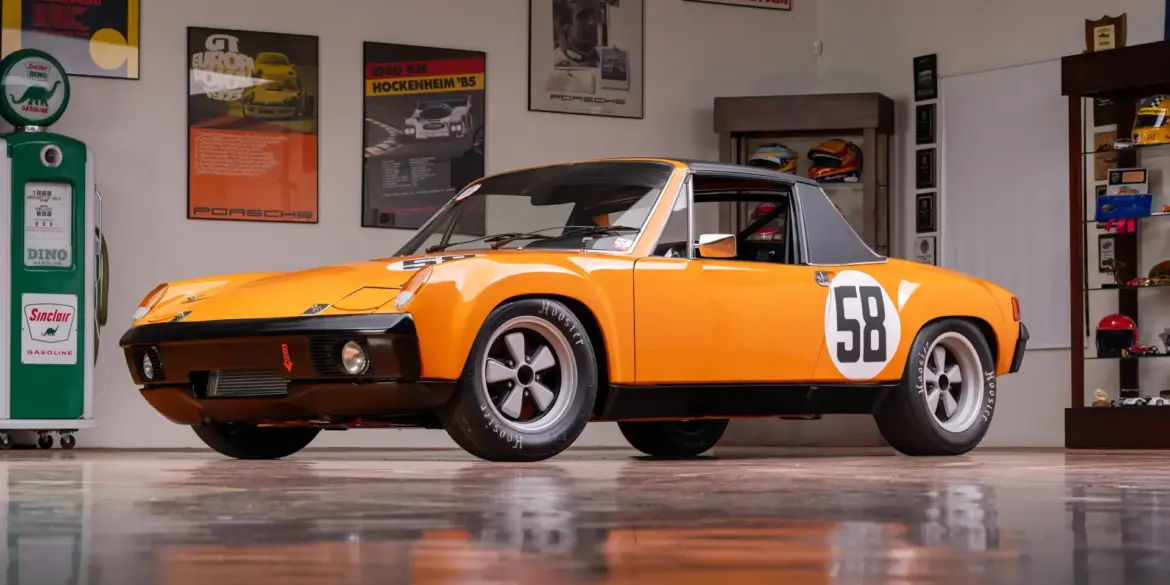 Gelber Porsche 914/6 R von 1970 mit Startnummer 58 in einer Garage, umgeben von Motorsport-Postern.