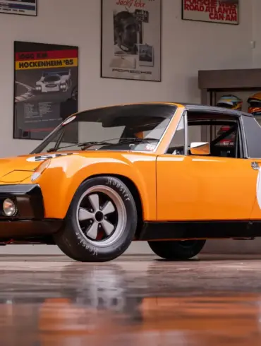 Gelber Porsche 914/6 R von 1970 mit Startnummer 58 in einer Garage, umgeben von Motorsport-Postern.