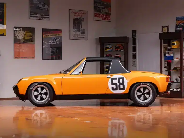 Seitenansicht eines orangefarbenen Porsche 914/6 R mit Startnummer 58 in einer automobilen Sammlung