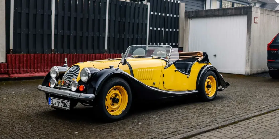 Morgan 4/4 Competition Baujahr 1971 in schwarz-gelber Farbkombination, Cabriolet, frontal seitlich abgelichtet.