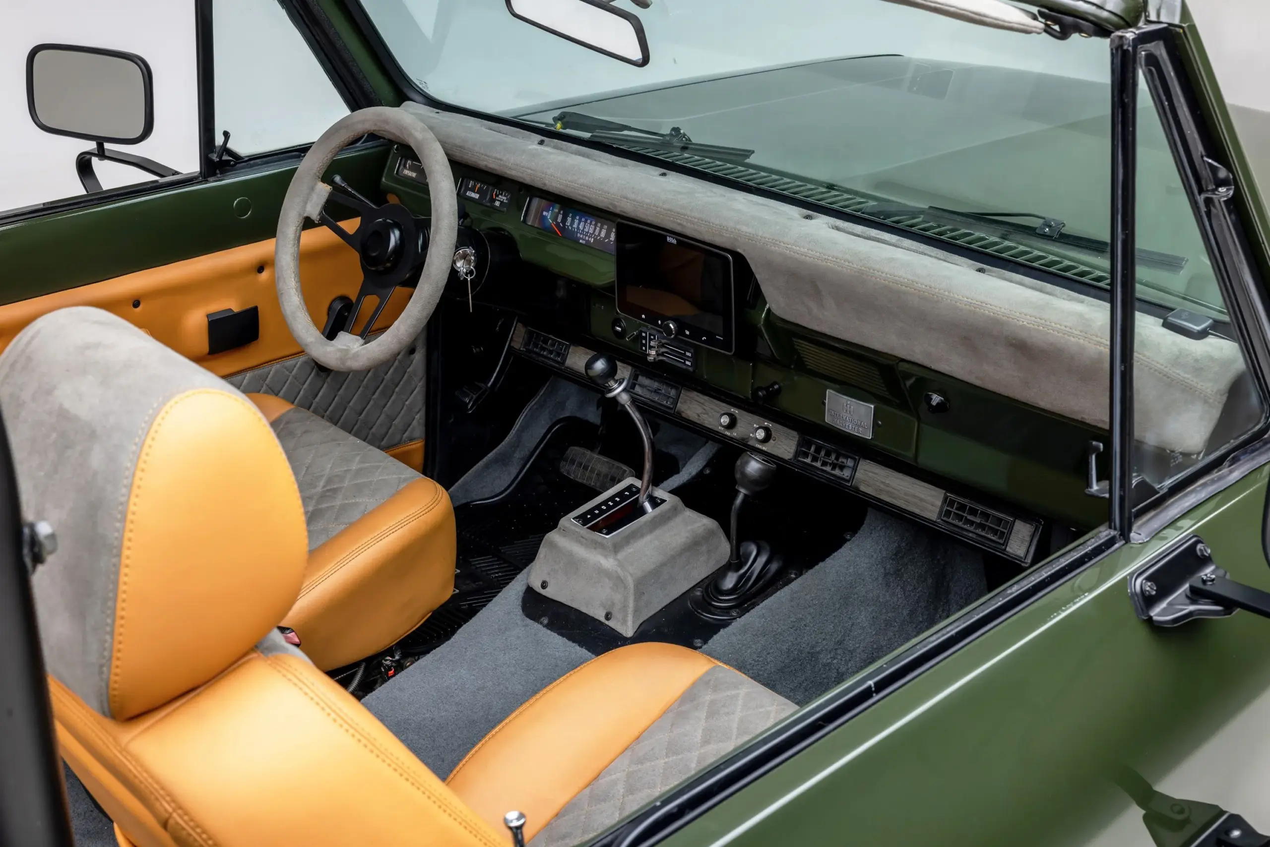 Innenraum eines restaurierten International Harvester Scout II Traveler von 1978 mit zweifarbigen Vinyl- und Microsuede-Sitzen, grauem Teppich und modernisiertem Armaturenbrett.