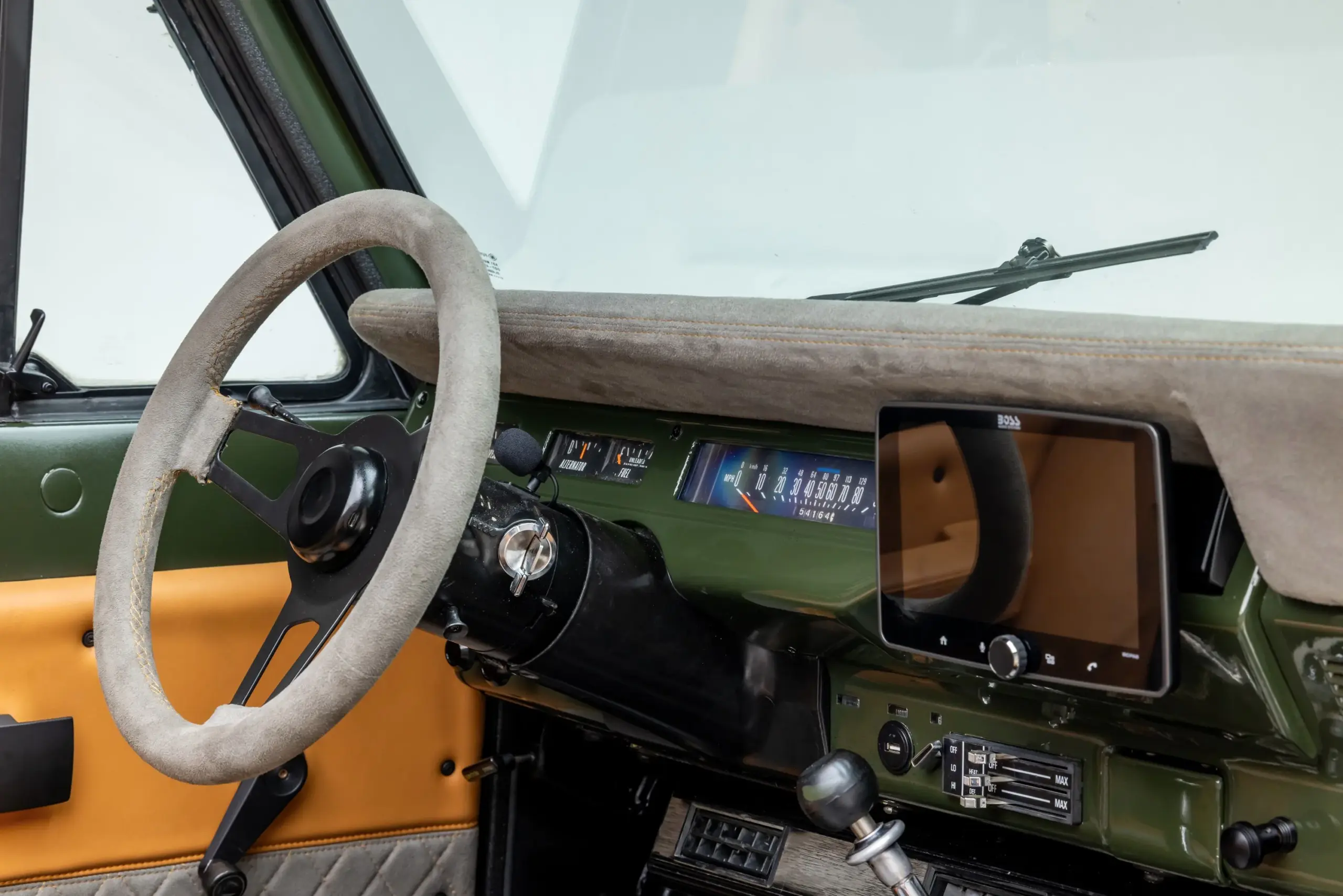 Innenansicht des Scout II Traveler mit grünem Metallarmaturenbrett, Microsuede-Lenkrad, klassischen Instrumenten und integriertem Boss-Touchscreen.