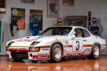 Rennversion des Porsche 924 GTP Baujahr 1980 in einer Ausstellung mit historischen Rennanzügen und Motorsport-Postern
