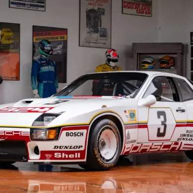 Rennversion des Porsche 924 GTP Baujahr 1980 in einer Ausstellung mit historischen Rennanzügen und Motorsport-Postern